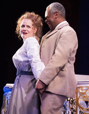 Maria scoonching back into Toby, in tan plaid sport jacket and pans, holding her hands against piano